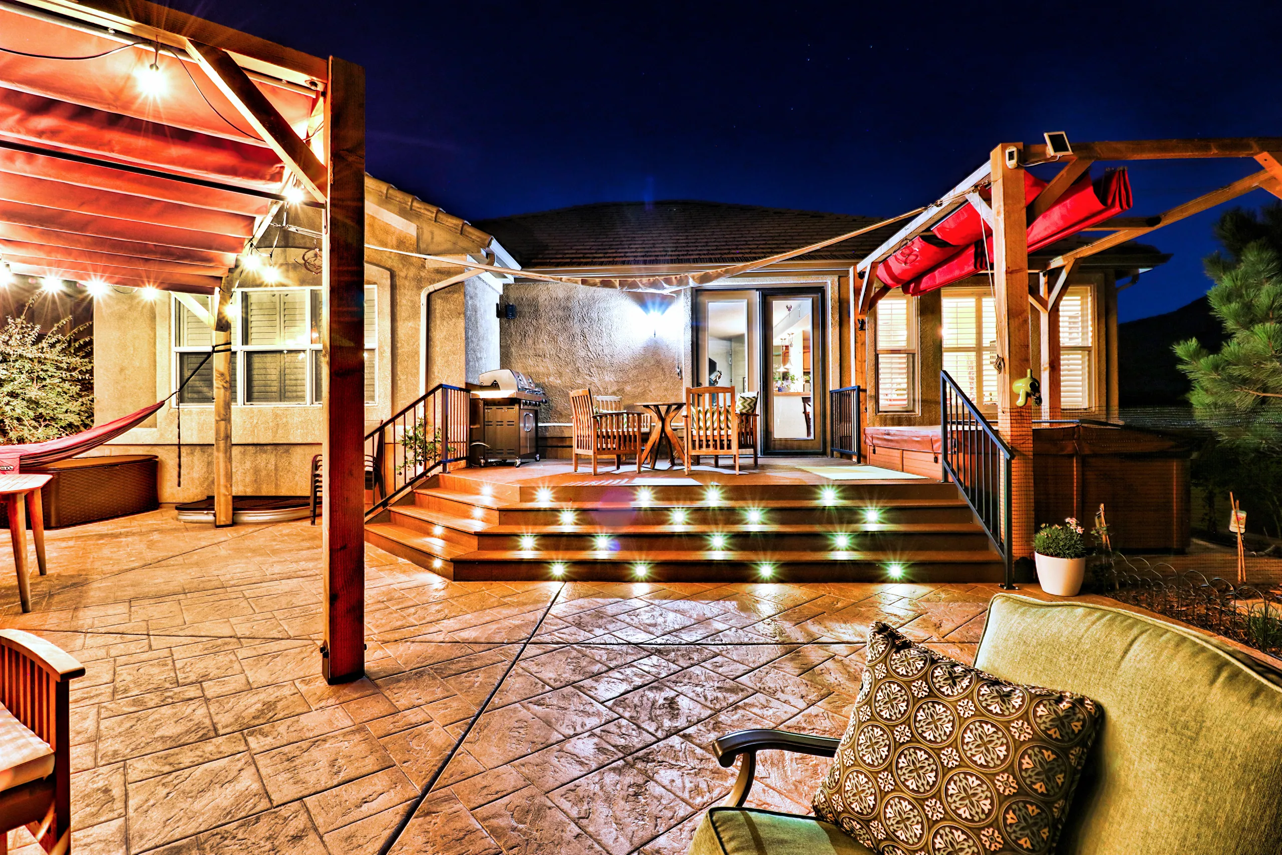 A lit deck and stamped patio under cedar pergolas at dusk at Sierra Oaks