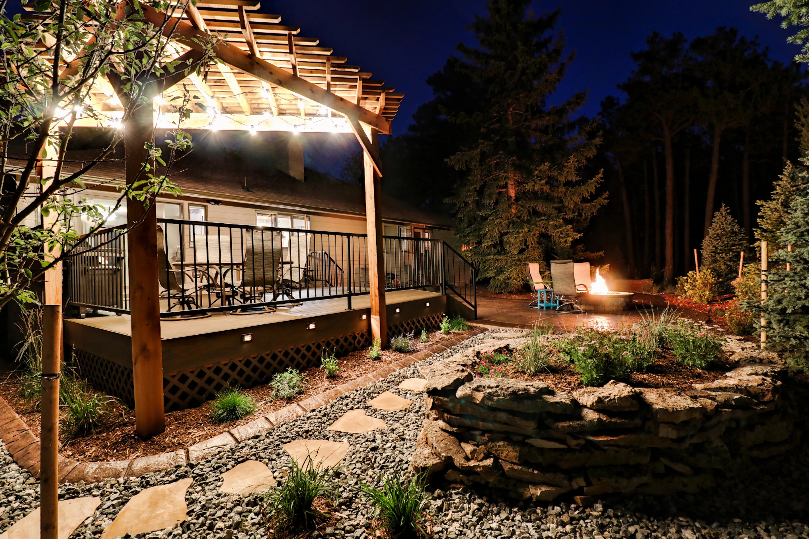 A cedar pergola lit with string lights over a deck at night